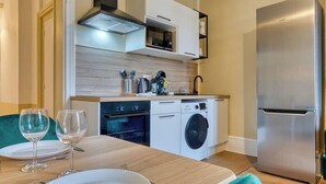 A modern kitchen with a stainless steel refrigerator, built-in oven, microwave, and washing machine.