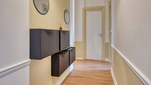 A hallway with a dark-colored console table against a cream-colored wall, flanked by two round mirrors.