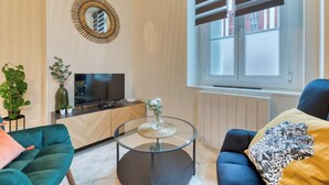 Un salon moderne comprenant un téléviseur, un canapé, une table basse et des objets de décoration.