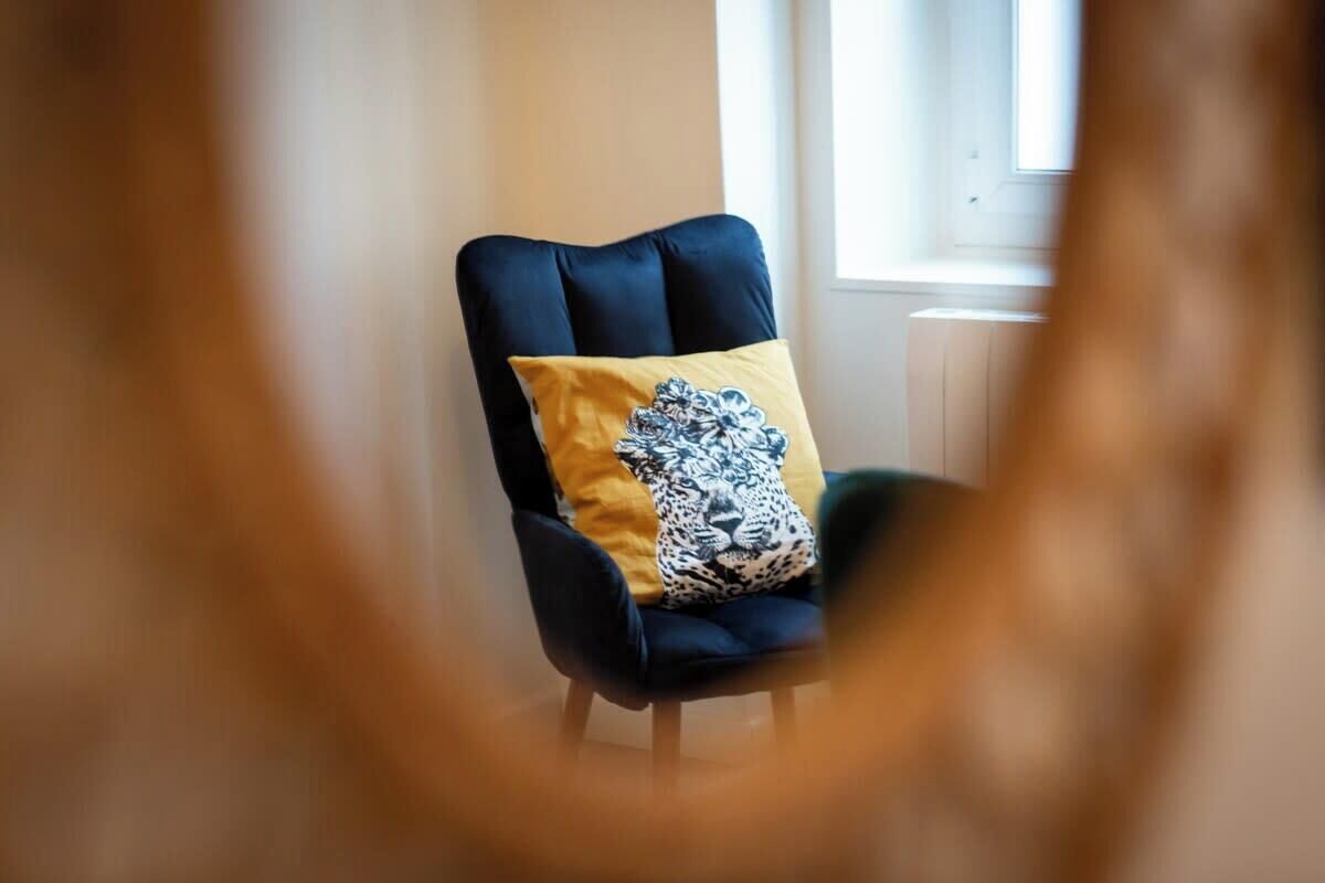 A chair with a dark backrest and a yellow cushion with a black and white pattern.