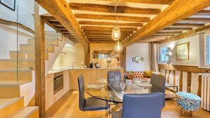 Een moderne keuken met houten balken, een glazen eettafel en een trap.