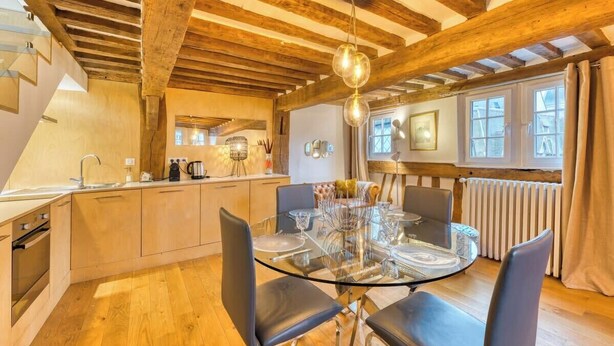 Een moderne keuken met houten balken, een glazen eettafel en een inbouwoven.