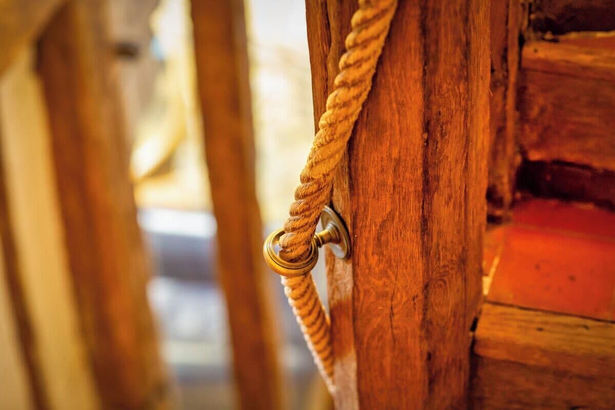 Un primo piano di una porta in legno con maniglia in corda e anello metallico.