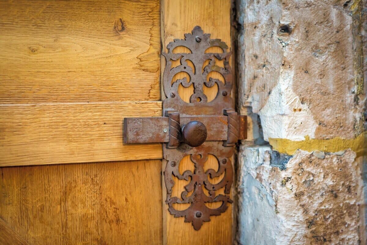 A wooden door with a metal latch and decorative metalwork.