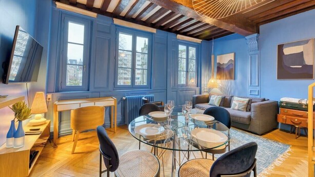 Un salon moderne avec une table à manger en verre, des sièges confortables et de grandes fenêtres.