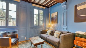 Une pièce avec un mur bleu, un canapé, une table et un radiateur.