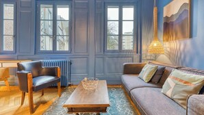 Une pièce avec un mur lambrissé bleu, une table en bois, un canapé en cuir et un luminaire suspendu.