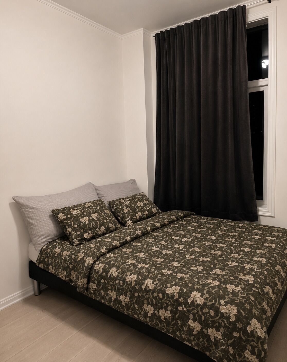 Une chambre à coucher avec un lit, une fenêtre avec des rideaux et une veilleuse.
