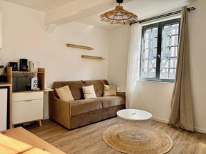 Un salon moderne avec un canapé marron, une table basse blanche et un tapis tissé.