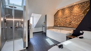 Une chambre d’hôtel moderne dotée d’une douche en verre, d’une grande fenêtre, d’un mur en briques, d’une baignoire et d’un lit.