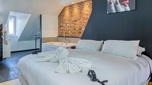 Une chambre moderne avec un grand lit, un mur en briques et une lucarne.