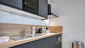 Ett modernt kök med en diskho i rostfritt stål, en kaffebryggare och en papperskorg.