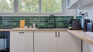 Une cuisine moderne avec un dosseret de carrelage vert, un plan de travail en bois et un robinet noir.