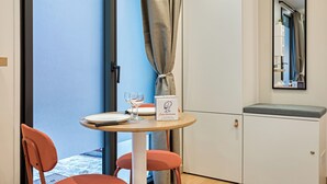 Een eetgedeelte met een tafel, stoelen, een glas, een bord en een menudoosje.