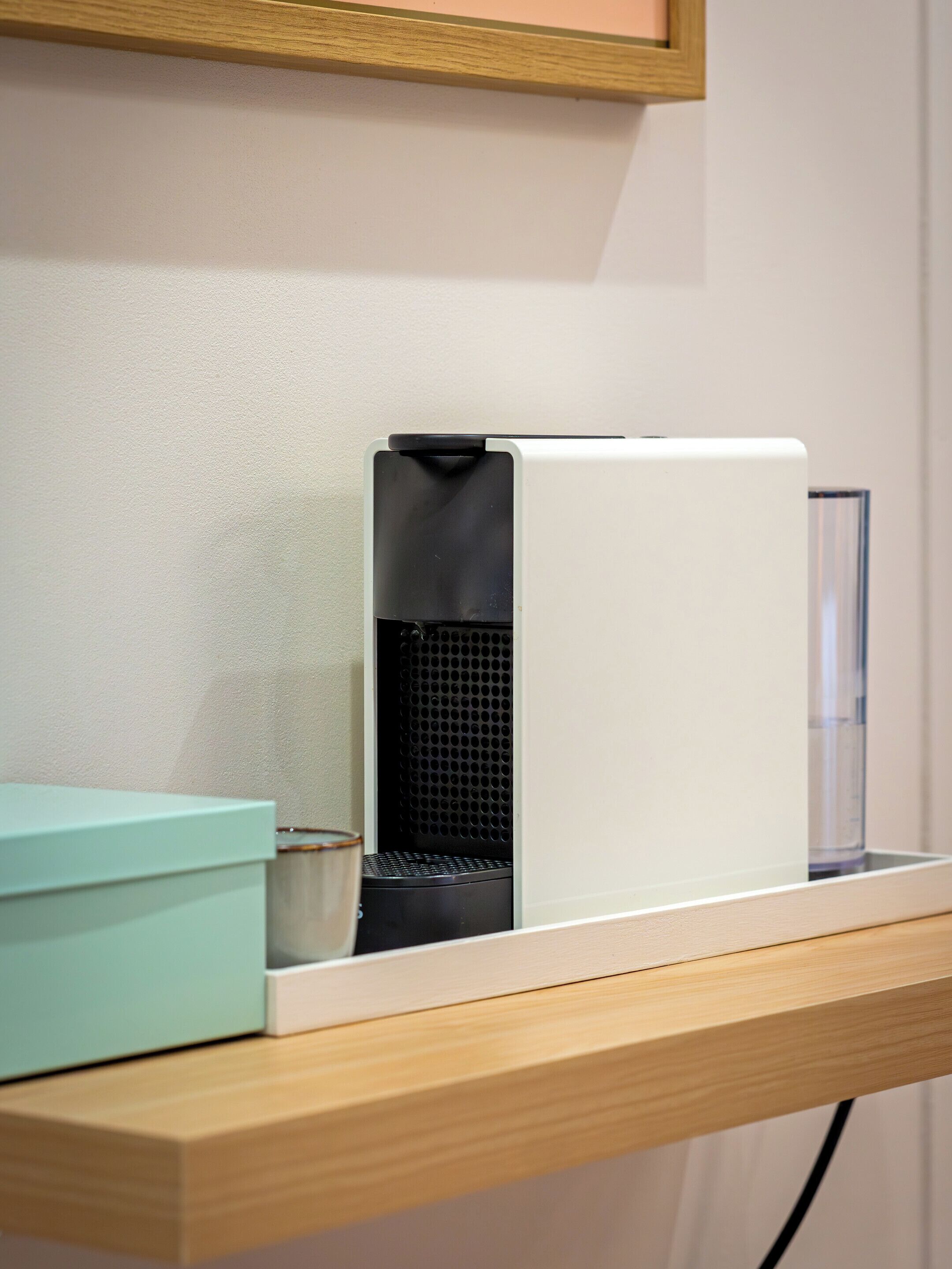 A white device on a shelf with a teal box and a clear container.