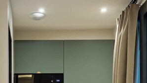 Een kleine keuken met een magnetron, een spoelbak en een houten aanrecht.