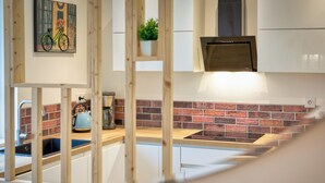 Une cuisine avec un mur recouvert de briques, une machine à café et une bouilloire posées sur le plan de travail.