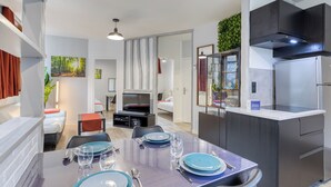 Een moderne keuken met donkere kasten, een inbouwfornuis en een eethoek met een tafel gedekt voor vier personen.