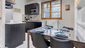 Een moderne keuken met donkere kastjes, een ingebouwde magnetron en een raam met ruitverdeling.