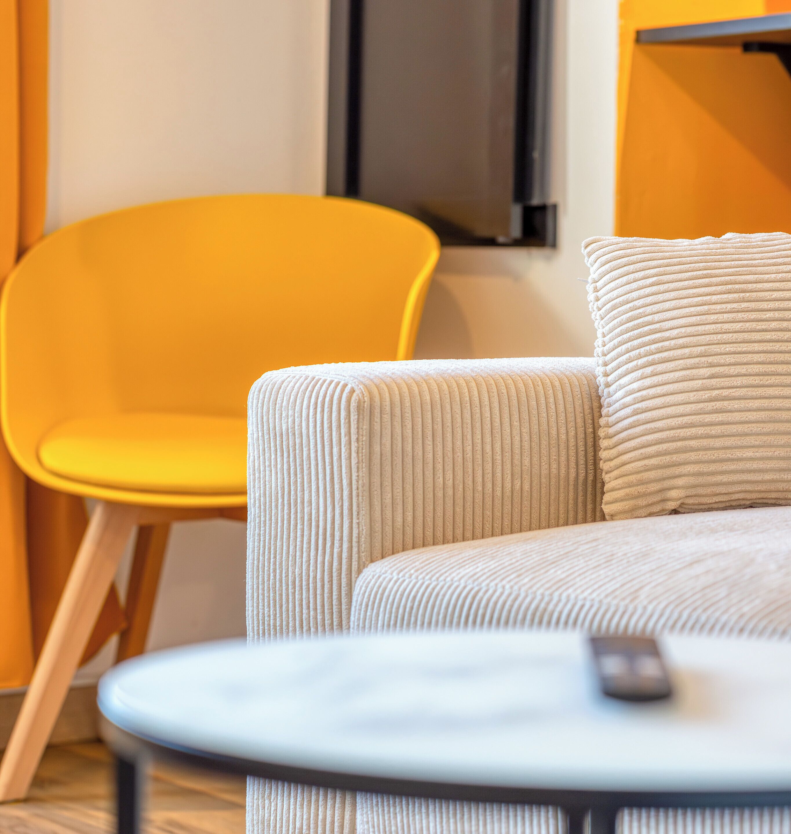 A modern living room with a sofa and a yellow chair.