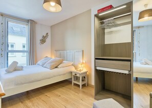 A modern bedroom with a bed, bedside table, and a built-in wardrobe with a hanging rack. - Bruno : charme à Rouen avec parking sécurisé (Rouen)