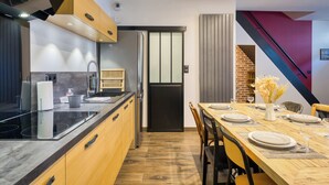 Eine moderne Küche mit schwarzem Arbeitsplatz, Holzschränken und einem Essbereich mit einem für vier Personen gedecktem Holztisch.