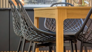 Un coin repas avec une table en bois et deux chaises dotées d’un dossier ajouré.