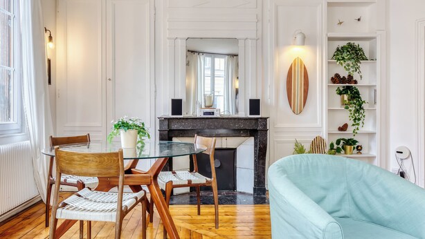 Un comedor con una mesa redonda de vidrio, sillas de madera y un sofá azul claro.
