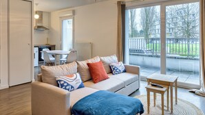 A modern living room with a sofa, a coffee table, and a dining area. - Le Nicole, un appartement en duplex avec balcon et place de parking. (Rouen)