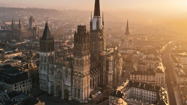 A cathedral with a tall spire, surrounded by historic buildings and a river. - L'Écrin Normand, un studio au cœur de Rouen (Rouen)