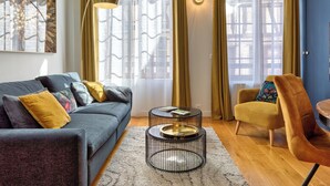A modern living room with a grey sofa, a round coffee table, and a yellow armchair. - L'escale du Gros-Horloge, une parenthèse prestigieuse au coeur de Rouen (Rouen)
