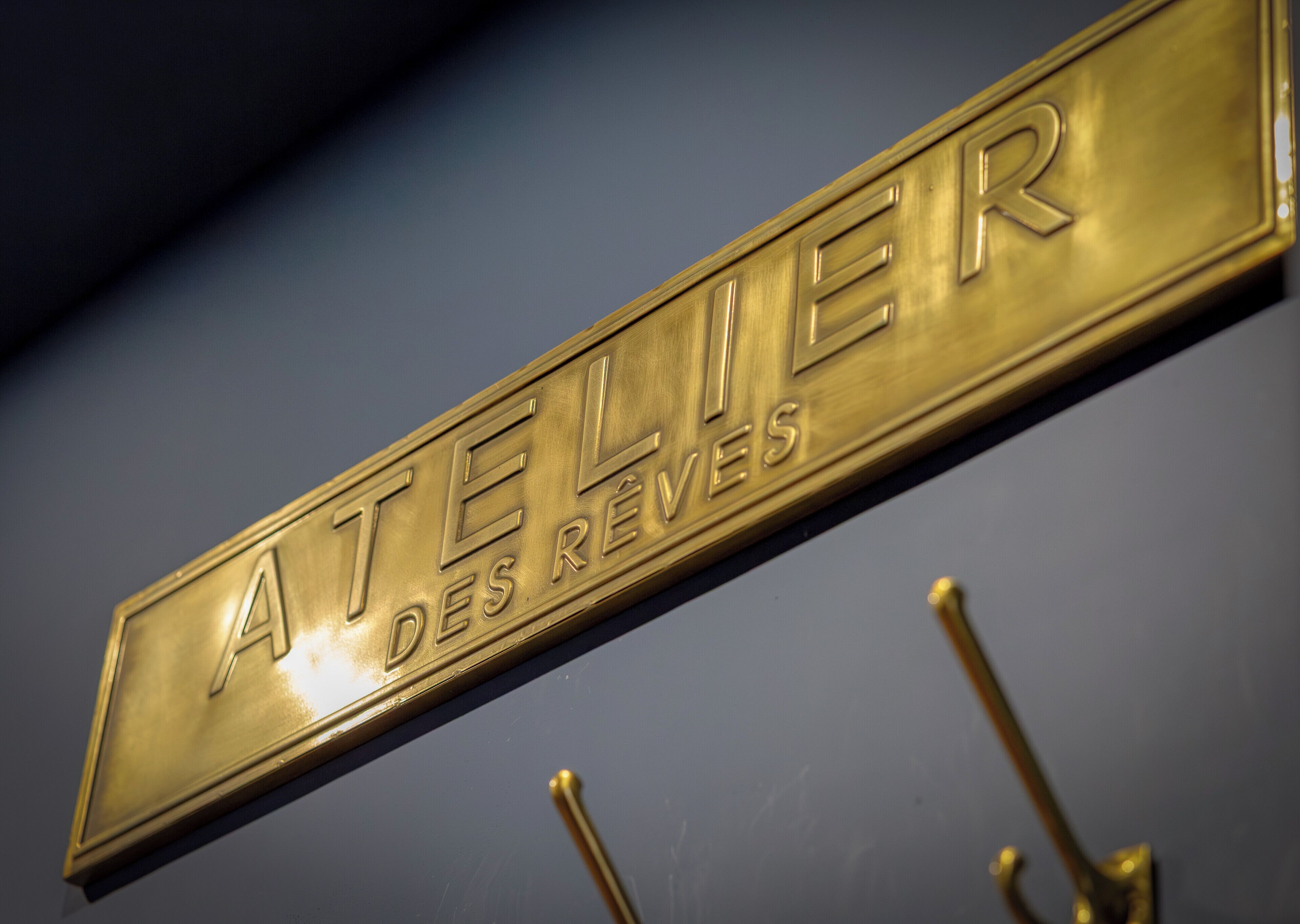 Une enseigne dorée portant l’inscription « ATELIER DES REVES », indiquant un magasin de bijoux.