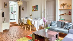 A dining area with a table set for four, a sofa, and a coffee table. - Agapanthes, jolie maison de ville à Rouen avec extérieur, terrasse (Rouen)
