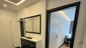 Une salle de bain moderne avec un grand miroir, un meuble-lavabo et un espace douche.