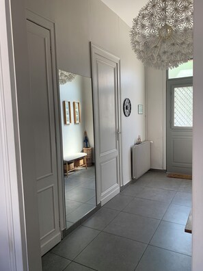 Un couloir avec un placard aux portes miroir, un luminaire décoratif au plafond et un radiateur.