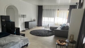 Un dormitorio moderno con cama, sofá, una mesita redonda y un mueble para televisión.
