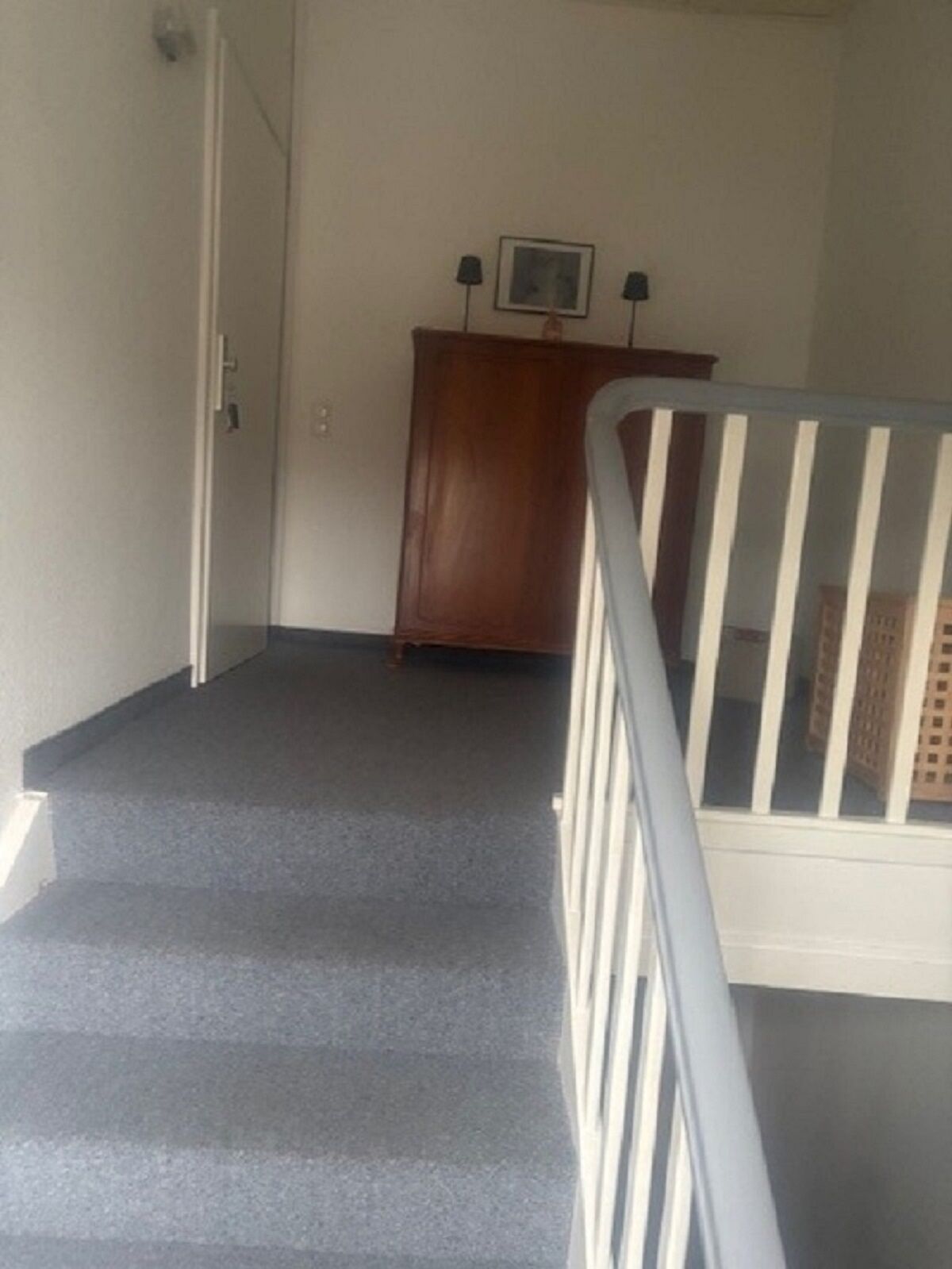 Una escalera con un armario de madera y dos lámparas en el rellano.