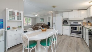 A modern kitchen with white cabinetry, a dining table with green chairs, and a built-in oven.