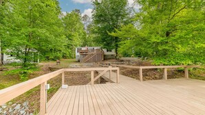 A wooden deck leading to a cabin surrounded by lush green trees.