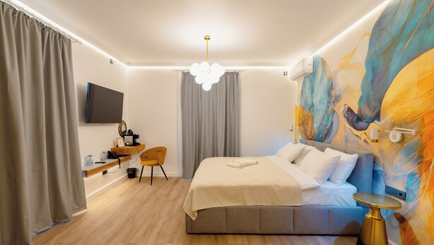Een moderne slaapkamer met een groot bed, een bureau en een aan de muur bevestigde televisie.
