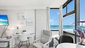 A modern room with a desk, chair, and a large window overlooking the ocean. - Oceanside Inn Studios by Brightwild (Daytona Beach Shores)