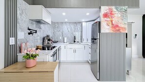 A modern kitchen with a marble backsplash, white cabinetry, and a central island with a sink.