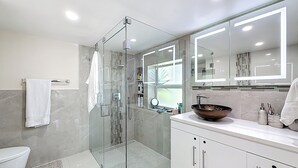 A modern bathroom with a glass-enclosed shower, a large mirror, and a vessel sink.