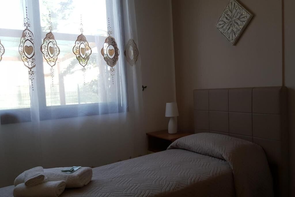 Una camera d'albergo con un letto, un comodino con una lampada e ornamenti decorativi appesi.