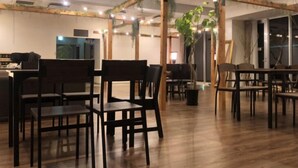 A spacious room with wooden flooring, multiple tables and chairs, and a ceiling with exposed beams and hanging plants. - kogikusou (Kikugawa)