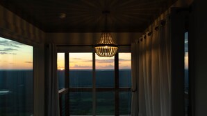 A room with a large window, a bed, and a hanging light fixture.