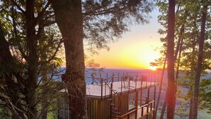 A wooden deck with a hammock and a bench overlooking a scenic view.