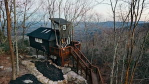 A cabin with a wooden deck and a stone pathway leading to a staircase.