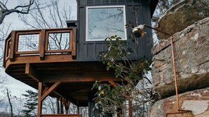 A modern cabin with a stone staircase leading up to a wooden deck.