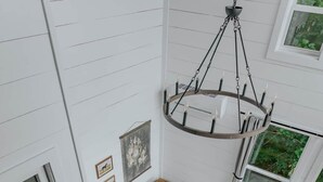 A spacious living area with a brown sofa, a patterned rug, and a chandelier. - The Artistree House A Treehouse in Rising Fawn (Rising Fawn)